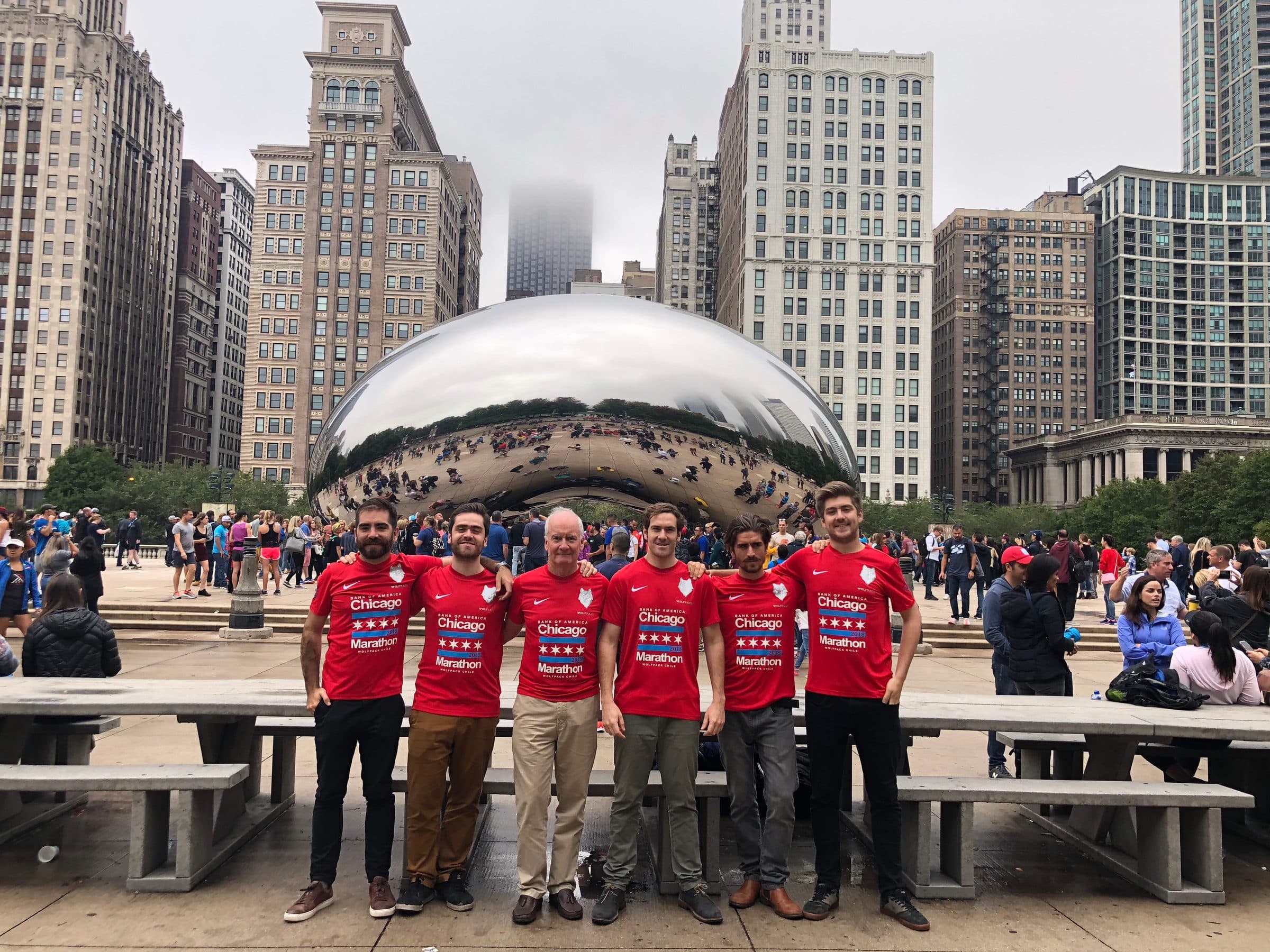 The six runners in red shirts in front of the Chicago Bean sculpture.